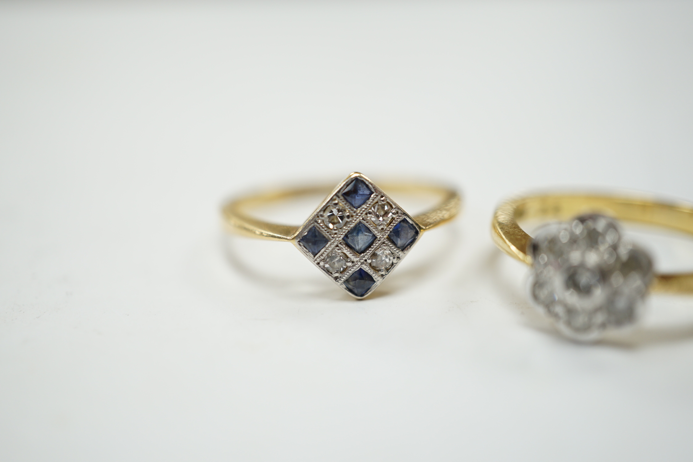 A 1920's 18ct, sapphire and diamond millegrain set cluster ring, size O/P, and a later 18ct gold and seven stone diamond set flower head cluster ring, gross weight 6.3 grams.